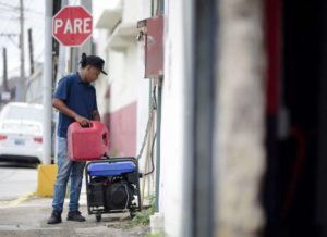 Juan Castro llena una planta de luz con gasolina afuera de su trabajo, en San Juan, Puerto Rico, el miércoles 18 de abril de 2018. (AP Foto/Carlos Giusti)
