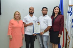 Los jóvenes José Alfonso Plácido Tineo y Wuady José Polanco, recibieron la patente de las manos de Sandy Lockward, directora de ONAPI y de Alma Fernández, directora General de Proindustria.